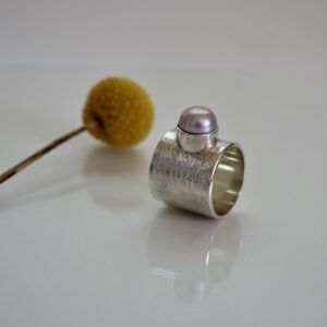 Breiter Silberring mit rosa Süßwasserperle und strukturierter Oberfläche